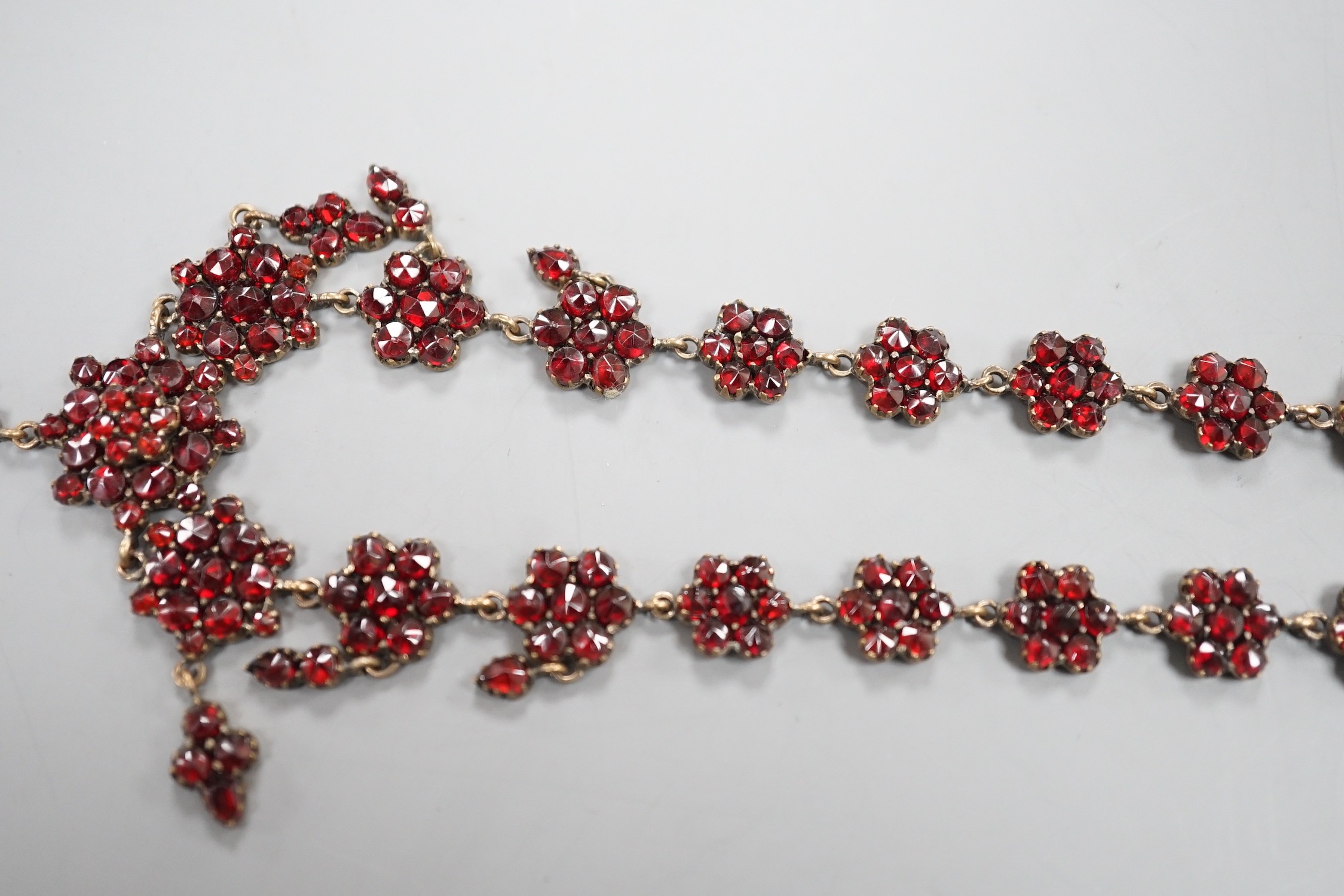 A late Victorian gilt and yellow metal, garnet cluster set drop necklace, 48cm.